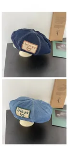 Detail of denim beret featuring contrast stitching and vintage embroidered heart patches