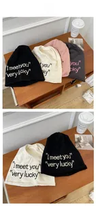 Detail view of cotton knit beanies featuring I meet you lettering in multiple colors