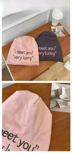 Detail showing knitted beanie hats in pink and grey with embroidered letters