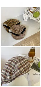 Detail view of plaid newsboy caps with vintage fabric labels and adjustable metal buckles