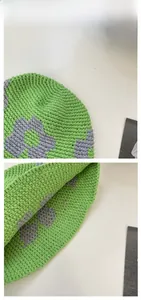 Détail d'un chapeau de pêcheur crocheté vert avec motifs floraux et texture tricotée