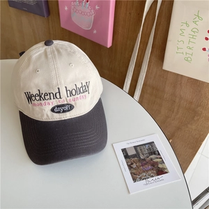 Retro two-tone baseball cap with Weekend embroidery on a white table in a cozy room