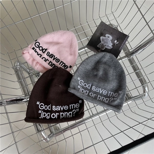 Three embroidered knit beanies in pink, brown, and grey inside a metal shopping basket