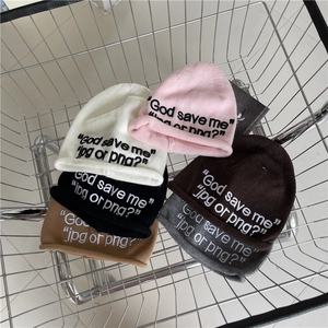 Chic letter embroidered knit beanies in multiple colors stacked in a metal basket