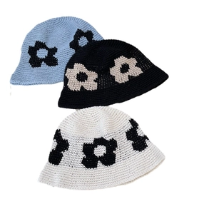 Trois bobs tricotés avec motifs floraux en bleu, noir et beige minimalistes