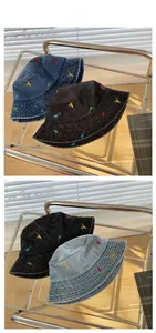 Detail of multi-colored dinosaur embroidery on washed denim bucket hats in various shades