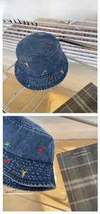 Detailed tile display of blue denim bucket hat with colorful mini dinosaur embroidery