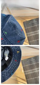 Detail of cute dinosaur embroidery on blue denim cotton bucket hat with inner wash label