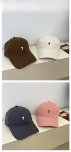 Detail showing embroidered number 7 on cotton baseball caps in brown, white, gray and pink