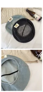 Detail view of retro washed denim beret hats in light blue and dark grey with NK fabric labels