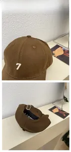 Detail view of dark brown baseball cap featuring white number 7 embroidery and metal strap