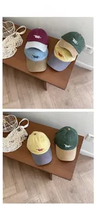 Détails de casquettes en coton bicolores avec broderie sun day sur un banc en bois