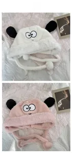 Close-up of plush puppy earflap hat with soft pom-poms and cartoon embroidery details