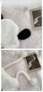 Detail of plush dog earflap hat featuring soft faux fur texture and long poms on ties