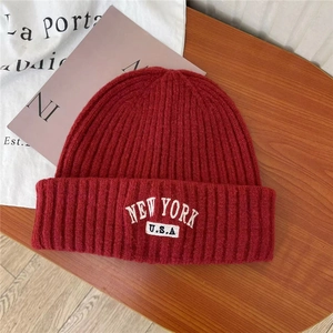Vintage red knit beanie with New York embroidery on a warm wood background
