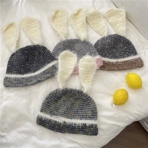 Bonnets tricotés avec oreilles de lapin en couleurs variées sur fond en tissu blanc