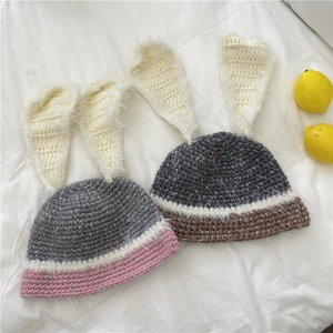 Bonnet en tricot avec oreilles de lapin en rose-gris et marron-gris sur tissu blanc