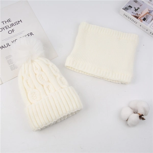 Detail of cream cable-knit winter hat set with fluffy pom-poms and warm inner lining