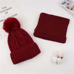 Detail of cable knit beanie and neck warmer set in burgundy with soft pompom finish