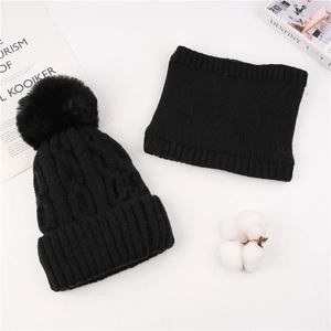 Detail of black cable-knit beanie with faux fur pom pom and matching neck gaiter