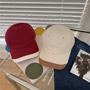 Two-tone cotton baseball caps in burgundy and beige colors displayed on casual background
