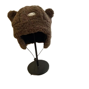 Cute brown plush winter trapper hat with bear ears and vintage label on soft fleece