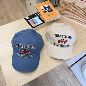 Blue and beige cotton baseball caps with fashion embroidery on light wood tabletop