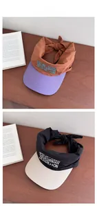 Detail of color-block visor caps with ribbon bow tie and Californian embroidery
