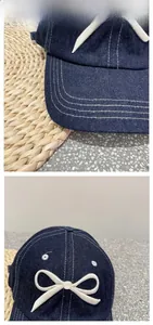 Detailed view of navy denim baseball cap with white bow embroidery and contrast stitching