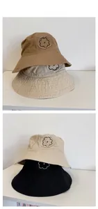 Detail showing stacked cotton bucket hats in khaki and black with floral embroidery and raw edges