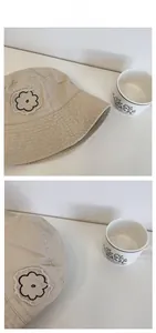 Detailed close-up of khaki canvas bucket hat with raw-edge flower embroidery patch