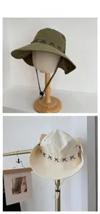 Detail of western cowboy hats in olive and beige with adjustable chin strap and braided decor