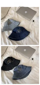 Detail of vintage washed denim bucket hat with sun embroidery and reinforced stitching