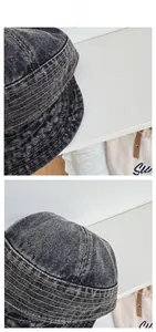 Detailed close-up showing the yellow stitching and washed grey denim fabric of the bucket hat