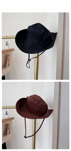 Detail of wide brim sun hats in black and brown with cross-stitch trim and chin cord