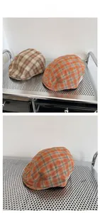 Vue détaillée de la texture du béret vintage à carreaux sur un présentoir métallique