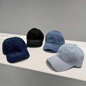 Classic denim baseball caps in four colors displayed on minimalist white geometric steps