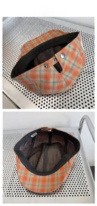 Détail d'un béret à carreaux orange et bleu montrant le bouton pression et la doublure interne