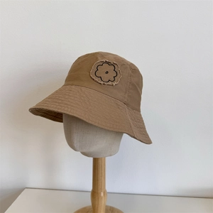 Khaki canvas bucket hat with vintage frayed flower embroidery on a wooden mannequin