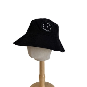 Minimalist black cotton bucket hat with floral embroidery on wooden mannequin head