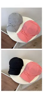 Close-up of bow knot baseball caps in pink, grey, and black on a white display stand