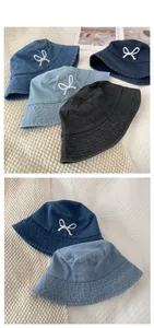 Flat lay of bow embroidery denim bucket hats in navy, light blue, and black styles