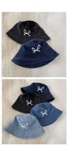 Detailed view of denim bucket hat featuring white embroidered bow and four color options