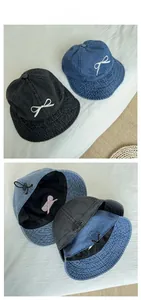 Detail of denim bucket hat showing bow embroidery and internal adjustable strap
