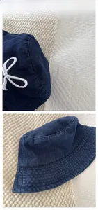 Detail of dark blue denim bucket hat with white bow embroidery and tile display