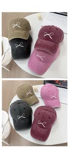 Detail of washed denim baseball caps with bow embroidery in four different colors