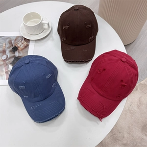 Distressed vintage cotton baseball caps in navy, burgundy, and coffee on a table