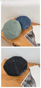 Detail view of denim beret hats in light green, blue and dark grey on a wooden table