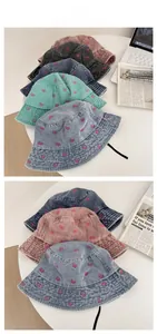 Detail of butterfly embroidery on washed denim bucket hats in multiple colors