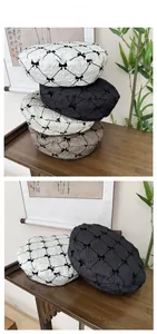 Close-up of seersucker beret with delicate black bow embroidery and textured diamond patterns